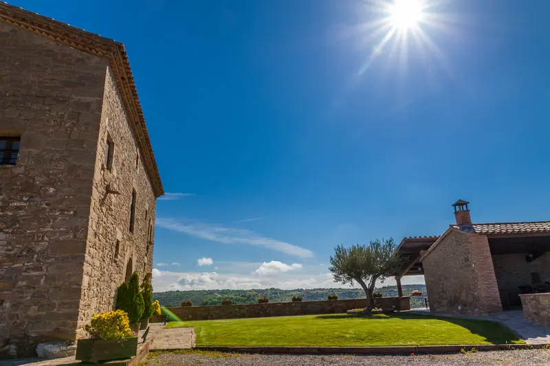 Façana de pedra de La Tor de Montclar amb jardí i vistes rurals