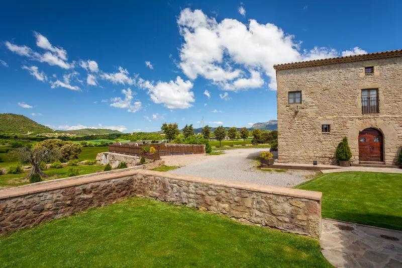 Façana principal de la masia amb jardí i camí de pedra